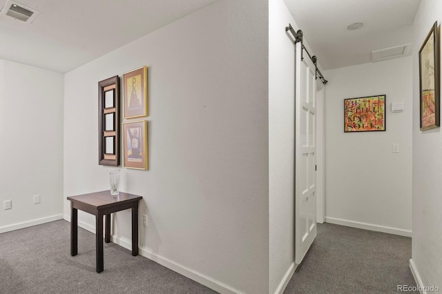 corridor with carpet floors, visible vents, a barn door, attic access, and baseboards