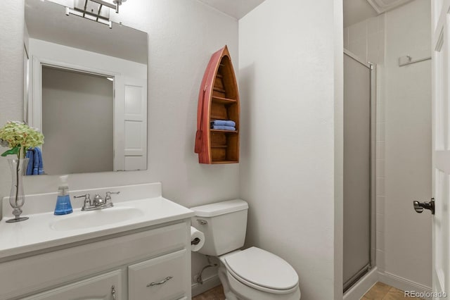 full bathroom with a stall shower, baseboards, vanity, and toilet