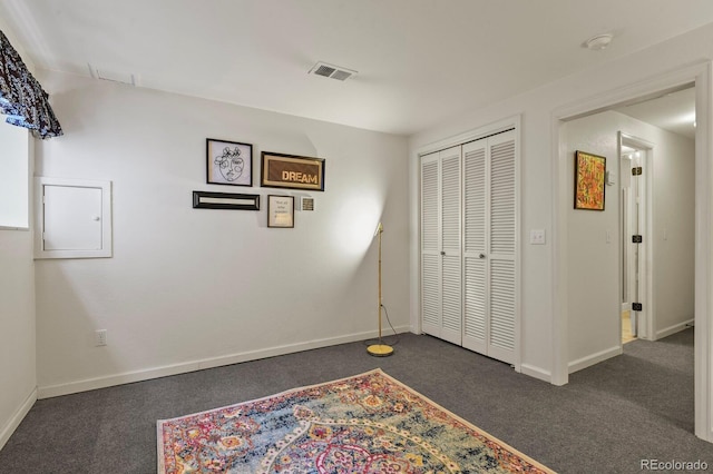 unfurnished bedroom featuring baseboards, visible vents, and dark carpet