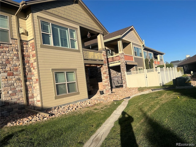 view of side of home with a lawn and a balcony