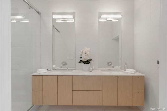 full bathroom featuring double vanity, a shower, tile walls, and a sink