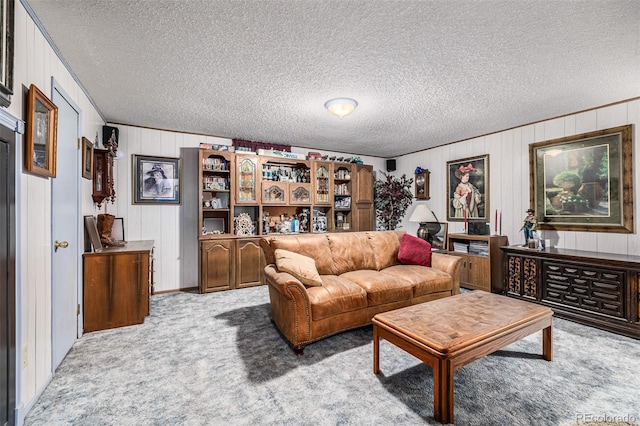 carpeted living room featuring wood walls and a textured ceiling