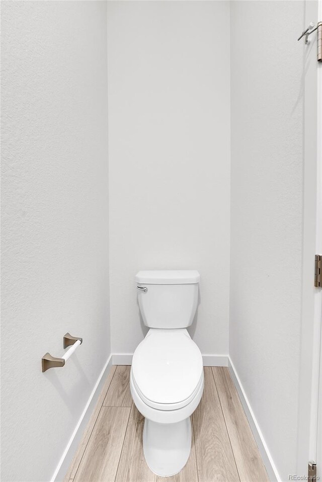 bathroom featuring wood finish floors, toilet, and baseboards