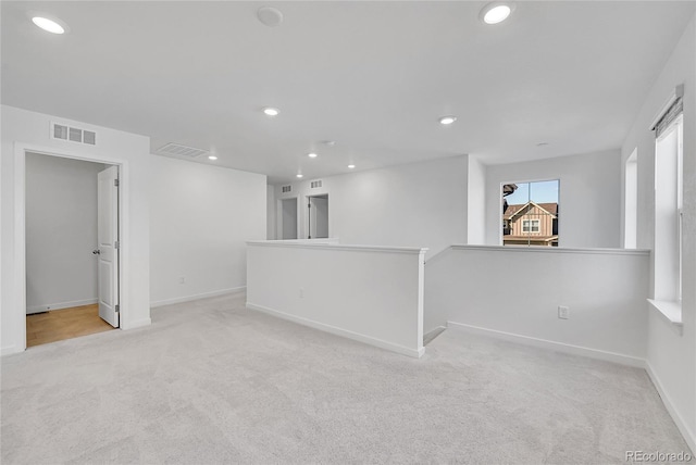 carpeted empty room featuring baseboards, visible vents, and recessed lighting