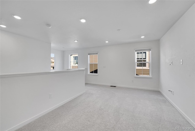 spare room with baseboards, recessed lighting, and light colored carpet