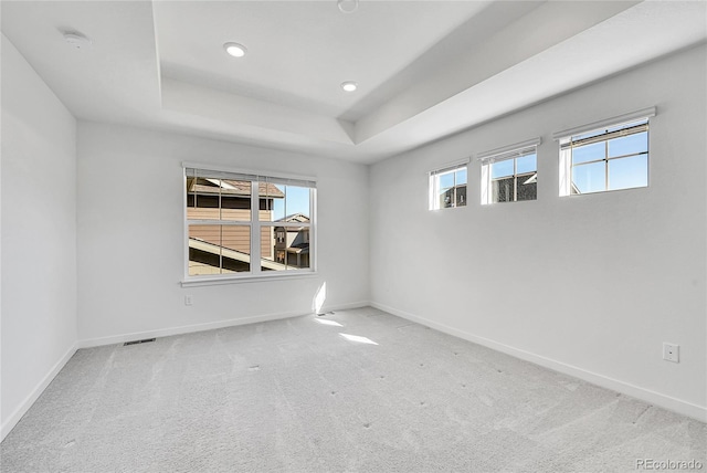 unfurnished room featuring carpet, baseboards, visible vents, and a tray ceiling