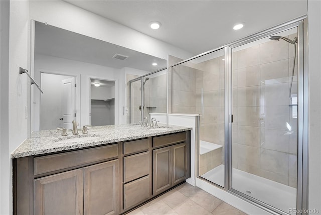 bathroom with double vanity, visible vents, a stall shower, a sink, and tile patterned flooring