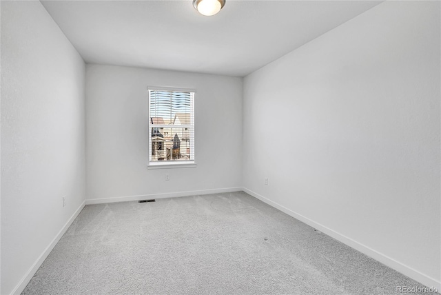 spare room with carpet flooring, visible vents, and baseboards