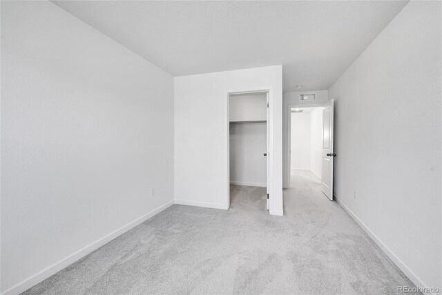 unfurnished bedroom featuring carpet, a walk in closet, visible vents, and baseboards