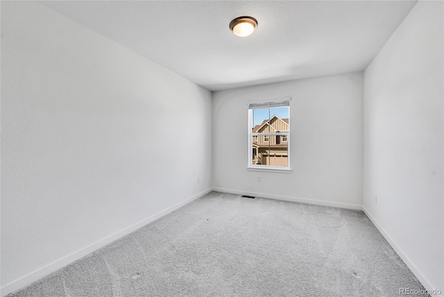 unfurnished room featuring carpet, visible vents, and baseboards