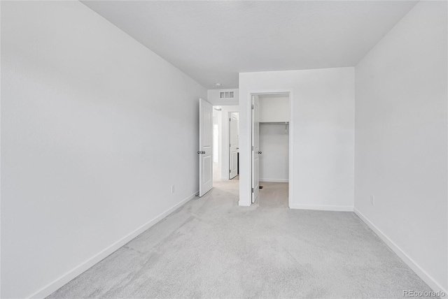 unfurnished bedroom with baseboards, visible vents, carpet, a spacious closet, and a closet