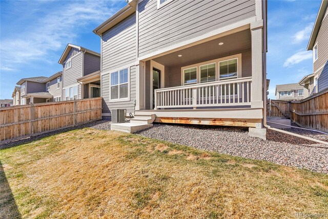 rear view of house featuring a fenced backyard, central AC unit, and a lawn