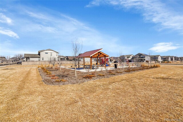 community jungle gym featuring a residential view, fence, and a yard