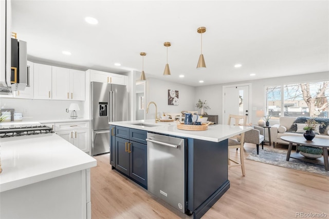 kitchen featuring white cabinetry, sink, hanging light fixtures, a kitchen island with sink, and stainless steel appliances