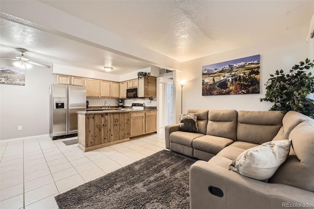 living area featuring light tile patterned floors, a ceiling fan, baseboards, and a textured ceiling