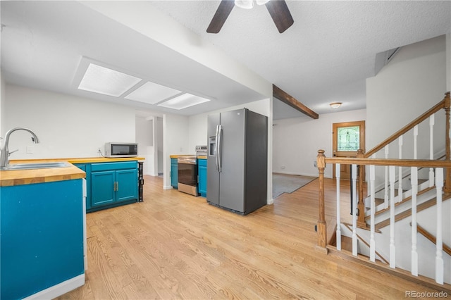 19398 E Eastman Pl, Aurora, CO 80013 - kitchen with stainless steel appliances, wood counters, a sink, blue cabinetry, and light wood-style floors