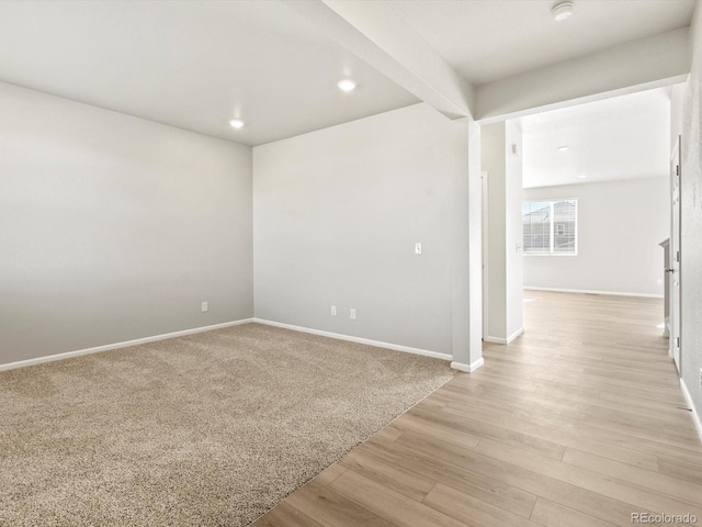 spare room featuring beam ceiling, recessed lighting, light wood-style flooring, and baseboards