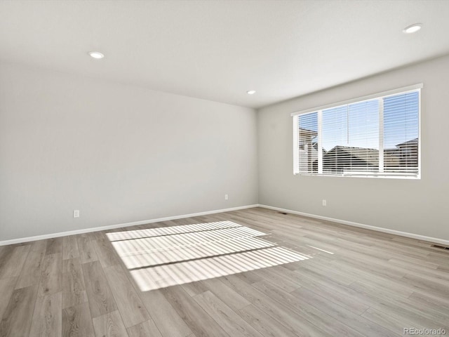 empty room with light wood finished floors, baseboards, and recessed lighting