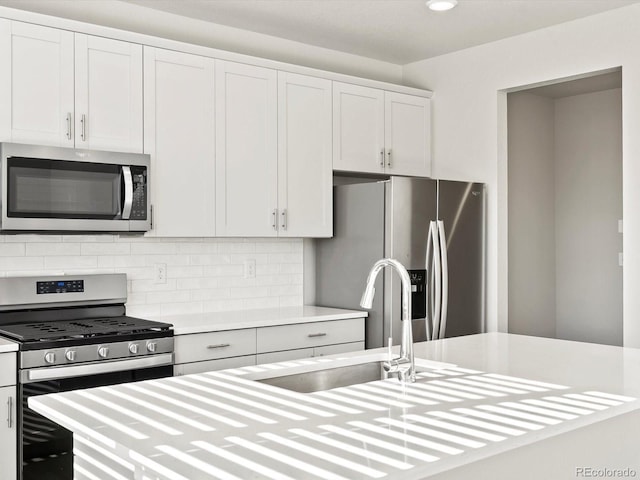 kitchen with stainless steel appliances, tasteful backsplash, light countertops, white cabinets, and a sink