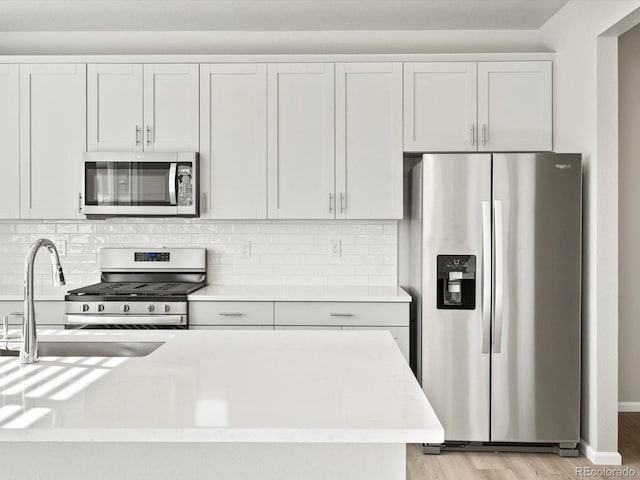 kitchen with stainless steel appliances, light wood-style floors, a sink, and decorative backsplash