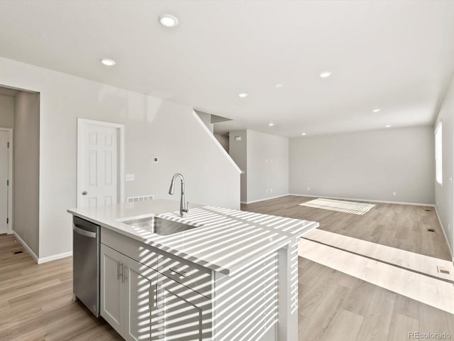 kitchen with light wood finished floors, recessed lighting, light countertops, stainless steel dishwasher, and a sink