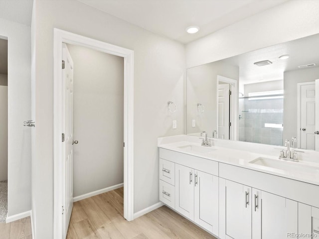 bathroom featuring a stall shower, a sink, and wood finished floors