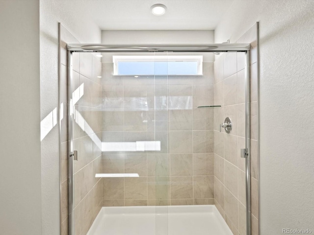 bathroom with a textured wall and a shower stall