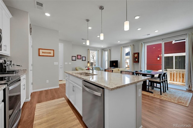 kitchen featuring white cabinetry, sink, stainless steel appliances, and an island with sink