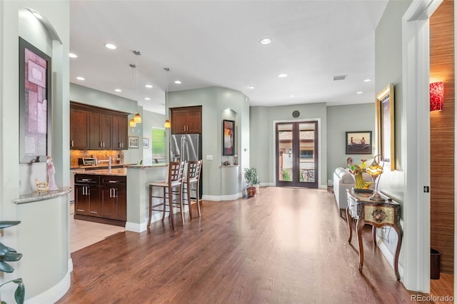 1344 S Saint Paul St, Denver, CO 80210 - kitchen featuring stainless steel fridge with ice dispenser, wood finished floors, an island with sink, hanging light fixtures, and a kitchen bar