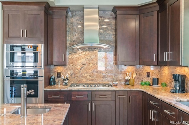 1344 S Saint Paul St, Denver, CO 80210 - kitchen with wall chimney range hood, appliances with stainless steel finishes, decorative backsplash, and dark brown cabinetry
