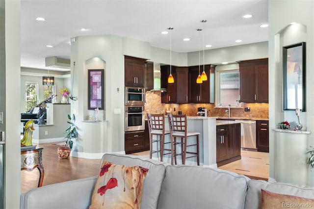 1344 S Saint Paul St, Denver, CO 80210 - kitchen with stainless steel appliances, dark brown cabinetry, light wood-type flooring, wall chimney range hood, and a center island