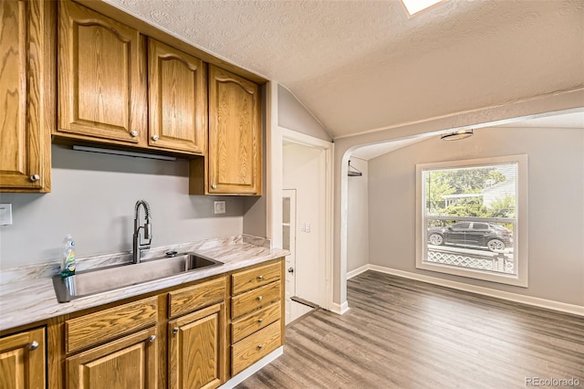 1187 Syracuse St, Denver, CO 80220 - kitchen with a textured ceiling, lofted ceiling, light wood-style flooring, light countertops, and brown cabinets