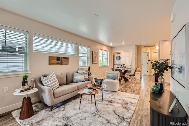 65 Avocet Ct, Longmont, CO 80501 - living room featuring stacked washer and clothes dryer, light wood-style flooring, and baseboards