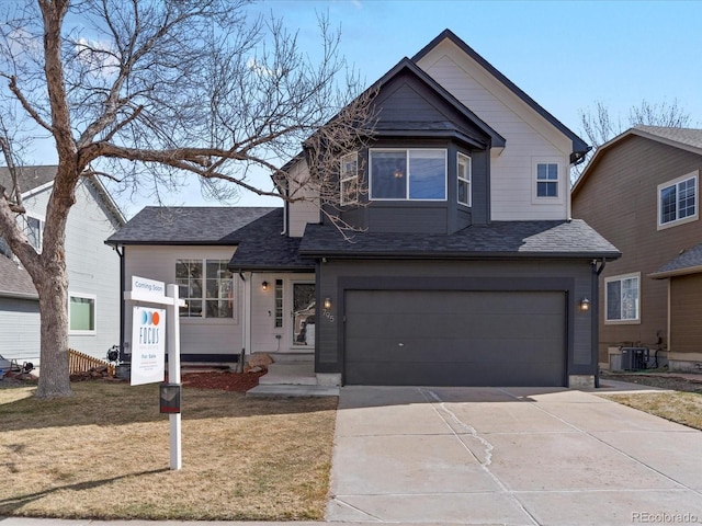 view of front of house with a front lawn, roof with shingles, central AC unit, a garage, and driveway