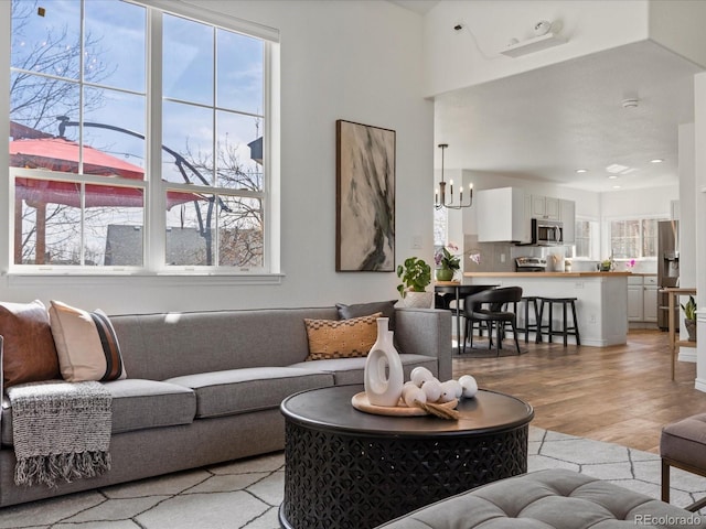 living room featuring a chandelier, a healthy amount of sunlight, and light wood-style floors