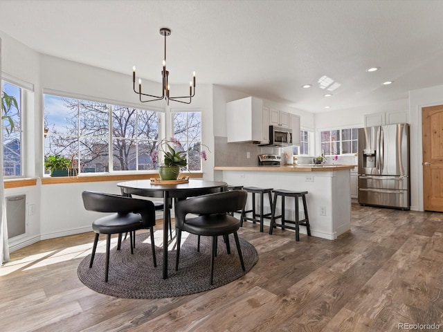 dining room with recessed lighting, a chandelier, plenty of natural light, and wood finished floors