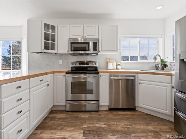 kitchen featuring dark wood finished floors, white cabinets, appliances with stainless steel finishes, and a sink