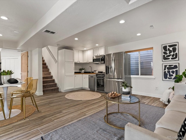 living room featuring visible vents, recessed lighting, light wood-style floors, baseboards, and stairs