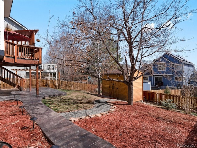 view of yard featuring a storage unit, a deck, an outdoor structure, and fence