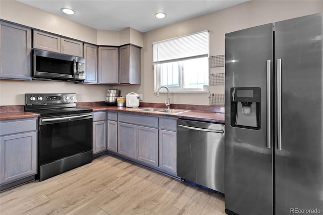 kitchen with gray cabinets, sink, appliances with stainless steel finishes, and light hardwood / wood-style flooring