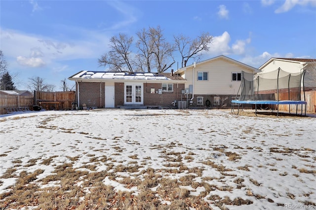 snow covered property featuring french doors, a trampoline, and cooling unit