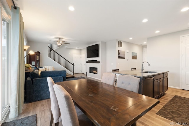16369 Alberta Dr, Parker, CO 80134 - dining space featuring a glass covered fireplace, light wood-style floors, stairs, ceiling fan, and recessed lighting