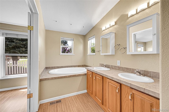 7870 Sunflower Grn Unit 151, Frederick, CO 80530 - bathroom with wood finished floors, a garden tub, vaulted ceiling, and double vanity