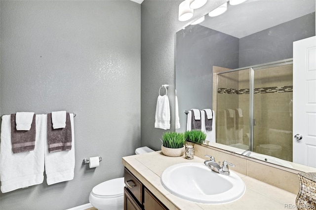 full bathroom with a shower stall, toilet, vanity, and a textured wall
