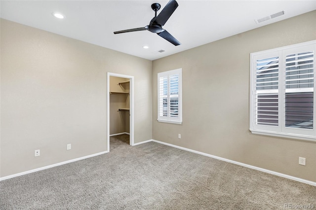 unfurnished bedroom with carpet, baseboards, a walk in closet, recessed lighting, and a ceiling fan