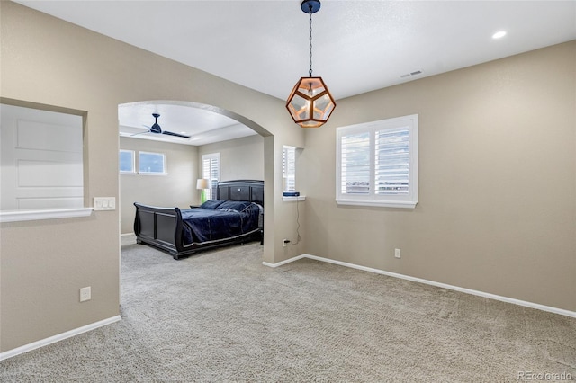 bedroom featuring carpet flooring, arched walkways, and baseboards