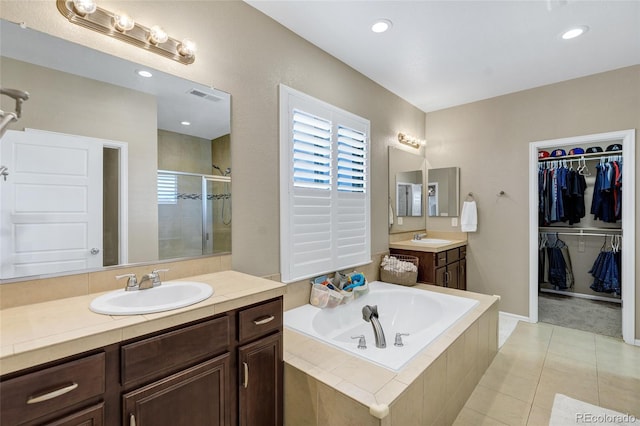 full bath with a shower stall, a bath, two vanities, tile patterned floors, and a walk in closet