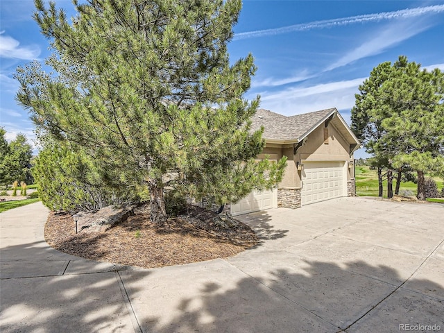 view of front of home with a shingled roof, concrete driveway, stucco siding, a garage, and stone siding