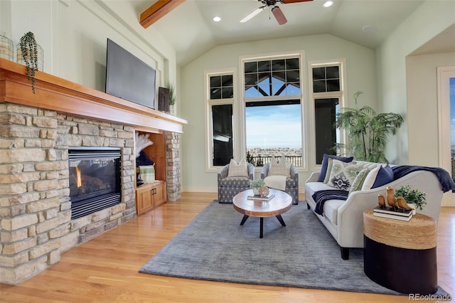 living area with a fireplace, a ceiling fan, lofted ceiling, and light wood-style floors