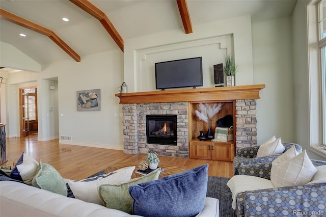 living area featuring visible vents, vaulted ceiling with beams, baseboards, a fireplace, and wood finished floors